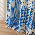 Hem of the blue geometric dots curtain with cream tassels on a light oak floor