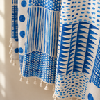 Close-up of cobalt blue dots, triangles and stripes patchwork print with cream tassels