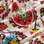 Close-up of red, mustard, blue and burgundy suzani flower medallion print on cream fabric