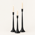 Set of 3 matte black iron taper candle holders in three heights with lit ivory taper candles