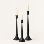 Set of 3 matte black iron taper candle holders in three heights with lit ivory taper candles