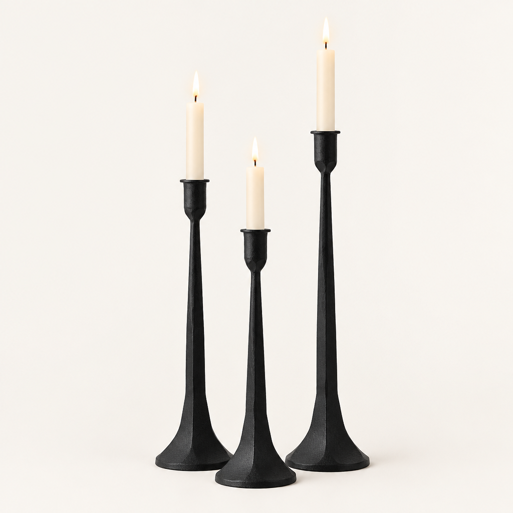 Set of 3 matte black iron taper candle holders in three heights with lit ivory taper candles