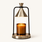 Melté candle warmer lamp in Champagne Noir, brass cone shade and black frame, warming an amber jar candle