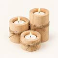 Bamboo Essence set of 3 natural wood tealight holders with jute bows, lit, on off-white background