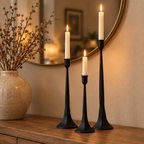 Black iron taper candle holders on a wooden entryway console under a round mirror