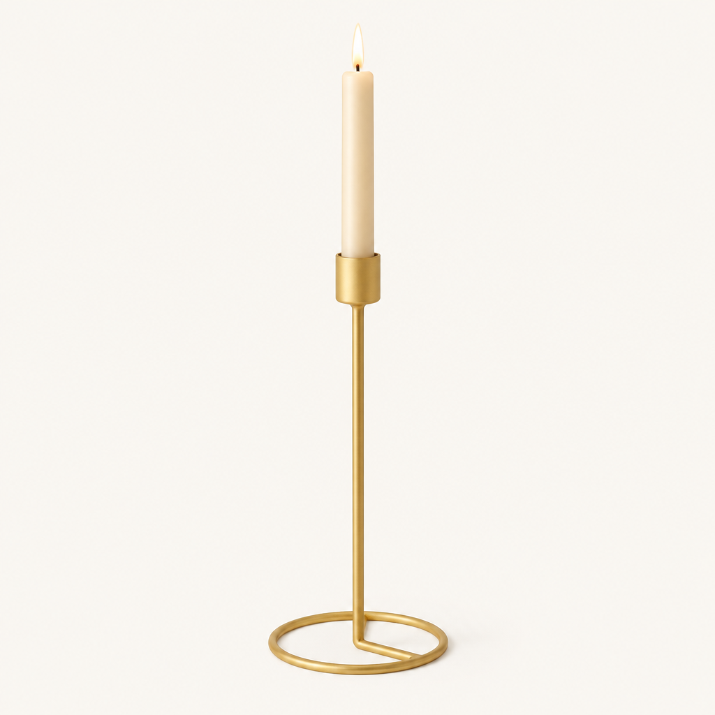 Large gold taper candlestick with a lit ivory taper candle on a warm off-white background
