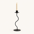 Small 9.4 inch matte black wavy iron taper candle holder with a lit candle