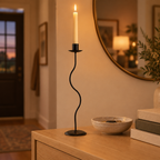 Large wavy iron candle holder on an oak entryway console table at dusk