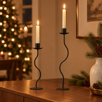 Wavy black candlesticks on a walnut dining sideboard with pine sprigs and holiday lights
