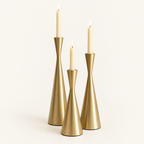 Set of 3 gold hourglass taper candlesticks in Golden Grace with lit ivory candles
