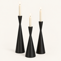 Set of 3 matte black hourglass taper candlesticks in Obsidian Elegance with lit ivory candles