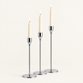 Set of 3 silver taper candlesticks in graduated heights with lit ivory candles