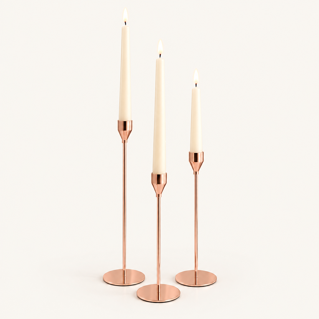 Set of 3 rose gold taper candlesticks in graduated heights with lit ivory candles