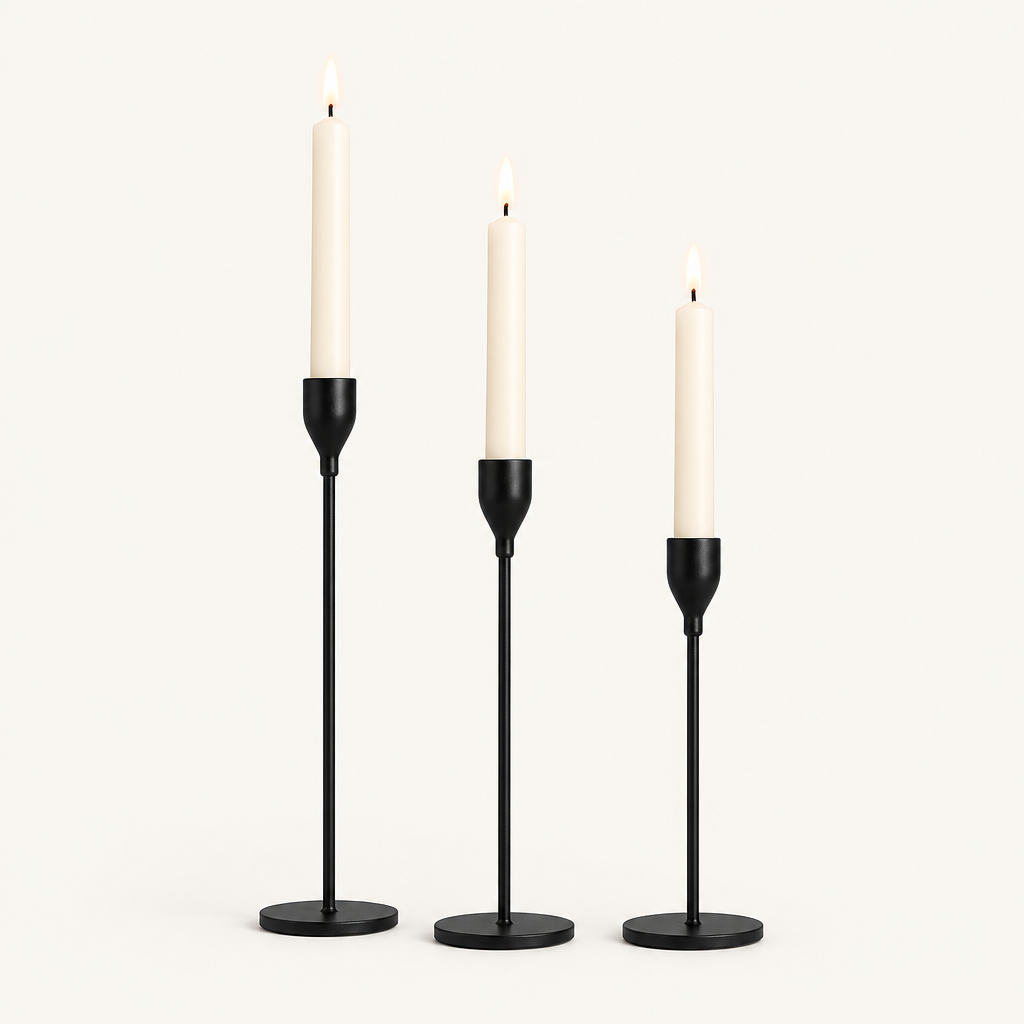 Set of 3 matte black taper candlesticks in graduated heights with lit ivory candles