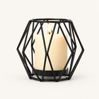 Geometric Black wireframe candle holder with a lit pillar candle on a warm off-white background