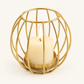 Sculptural Gold rounded wire candle holder with a lit pillar candle on a warm off-white background
