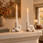 Pair of knot ceramic candle holders lit on a living room mantel in autumn