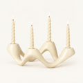 Cosmic Ripple white ceramic wave candelabra holding four lit twisted taper candles