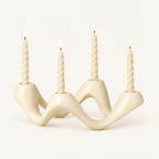 Cosmic Ripple white ceramic wave candelabra holding four lit twisted taper candles