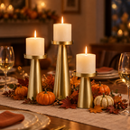 Brass pillar candle holders as a Thanksgiving table centerpiece with pumpkins and autumn leaves