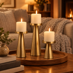 Gold pillar candle holders on a wooden tray on a living room coffee table in the evening
