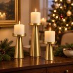 Gold pillar candle holders on a dining sideboard with pine sprigs and Christmas tree lights