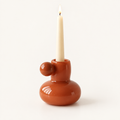 Celestial Nordic glass candle holder in burnt orange with a lit taper candle