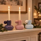 Purple, pink and blue glass candle holders lit on a holiday fireplace mantel