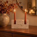 Travertine candle holder with terracotta tapers on a walnut sideboard with autumn branches