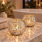 Silver Glow Sphere candle holders lit on a marble bathroom counter