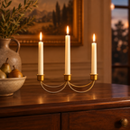 Gold three-candle holder lit on a walnut dining sideboard at dusk
