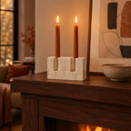 Polished travertine two-taper candle stand with terracotta candles on a walnut mantel