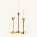 Set of 3 gold taper candlesticks in three heights with lit white candles