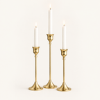 Set of 3 gold taper candlesticks in three heights with lit white candles