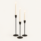 Set of 3 matte black metal taper candle holders with lit ivory taper candles