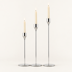 Set of 3 silver metal taper candle holders with lit ivory taper candles
