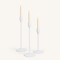 Set of 3 matte white metal taper candle holders with lit ivory taper candles
