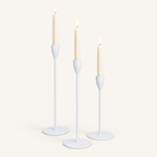 Set of 3 matte white metal taper candle holders with lit ivory taper candles