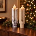 White marble and travertine Eclipse candle holders on a sideboard with pine and Christmas lights